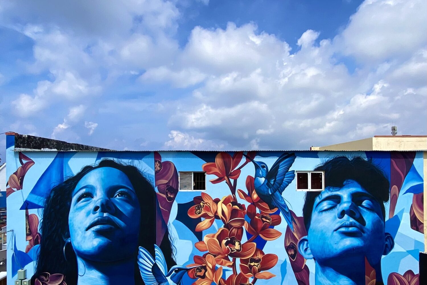 Mural Lo de aqui by Fio Silva and Sake Ink in San Nicolas, Aruba: a girl and a boy of Aruba painted in blue.