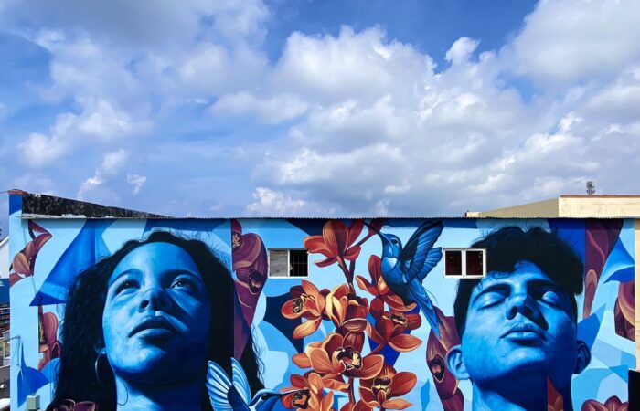 Mural Lo de aqui by Fio Silva and Sake Ink in San Nicolas, Aruba: a girl and a boy of Aruba painted in blue.