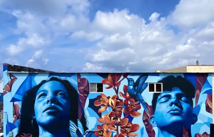 Mural Lo de aqui by Fio Silva and Sake Ink in San Nicolas, Aruba: a girl and a boy of Aruba painted in blue.
