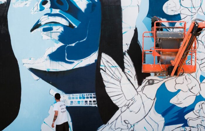A large blue and white portrait mural with doves on a wall in San Nicolas, Aruba, 2025.