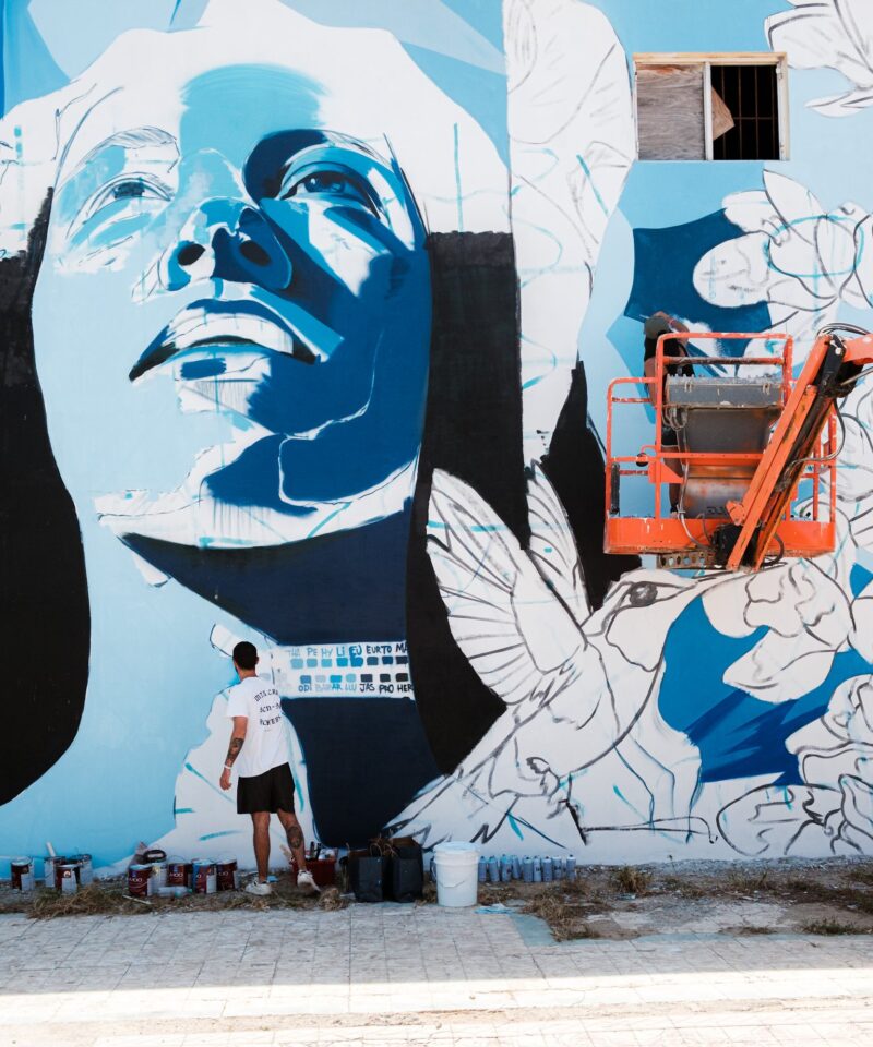 A large blue and white portrait mural with doves on a wall in San Nicolas, Aruba, 2025.