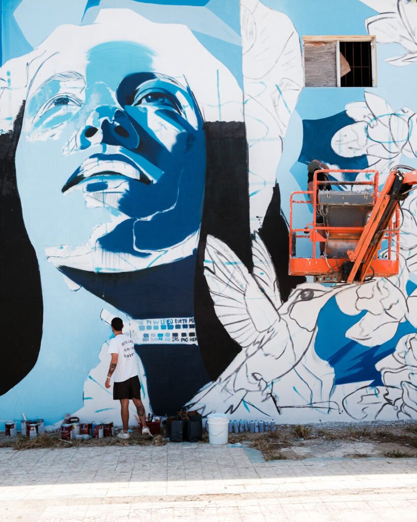 A large blue and white portrait mural with doves on a wall in San Nicolas, Aruba, 2025.