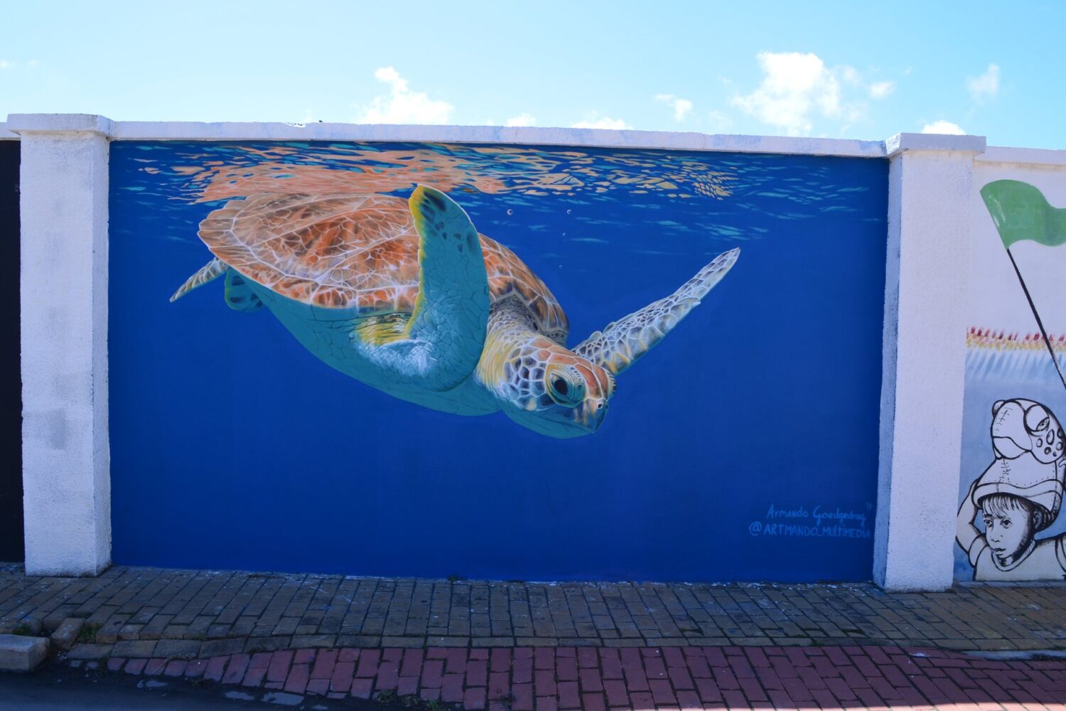 A green sea turtle painted swimming across a deep blue wall in San Nicolas, Aruba, 2024.